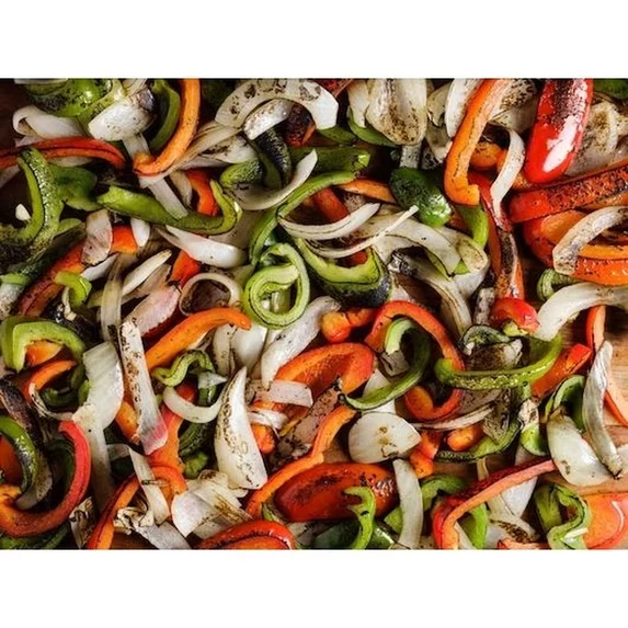 Sliced red, green and orange peppers with onions, charred on the flat top